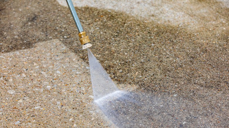 Pressure washing dirty concrete driveway. Home cleaning, maintenance and household chores concept